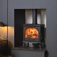 Wood-burning stove with glowing fire inside a dark room