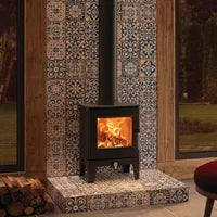 Wood-burning stove in a room with decorative tiles and a mirror.