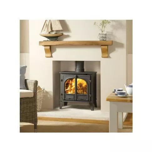 Wood-burning stove in a living room setting with a mantelpiece and decor.