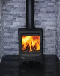 Wood-burning stove with flames inside, set against a gray brick wall.