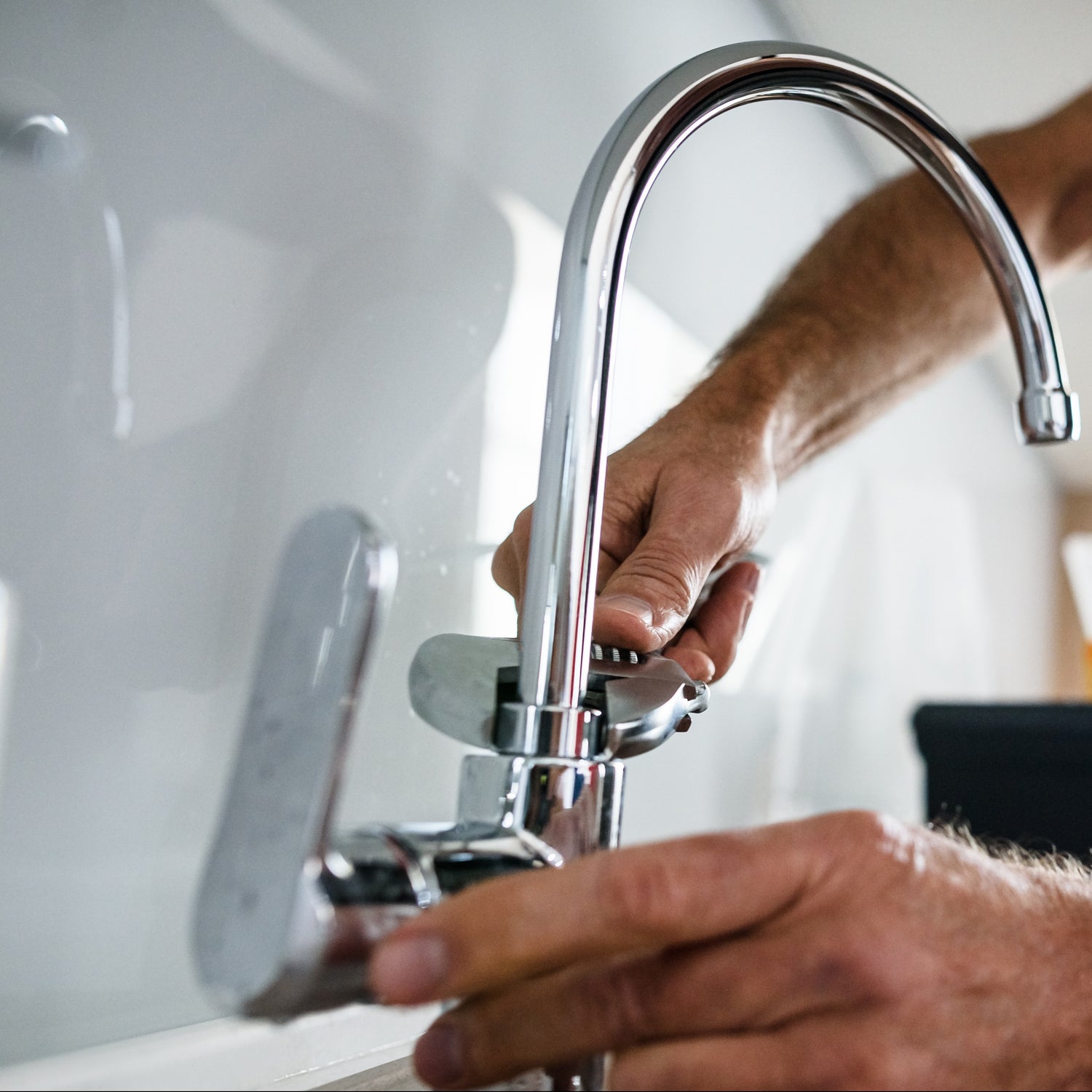 Person adjusting a modern kitchen tap .