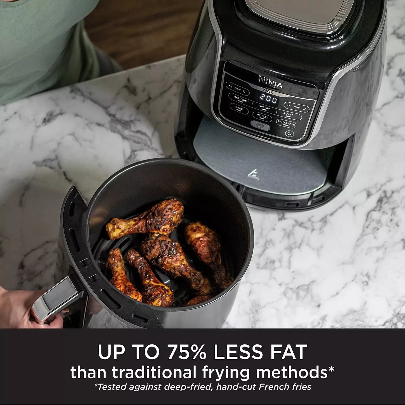 Ninja air fryer with cooked chicken drumsticks on a marble countertop
