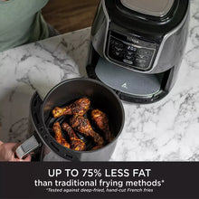 Ninja air fryer with cooked chicken drumsticks on a marble countertop