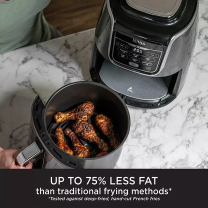 Ninja air fryer with cooked chicken drumsticks on a marble countertop