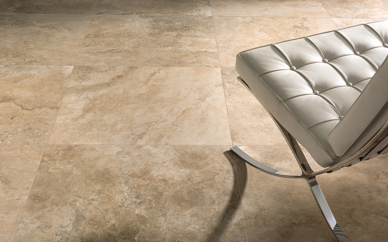 Beige tiles on a floor with a modern chair in the corner