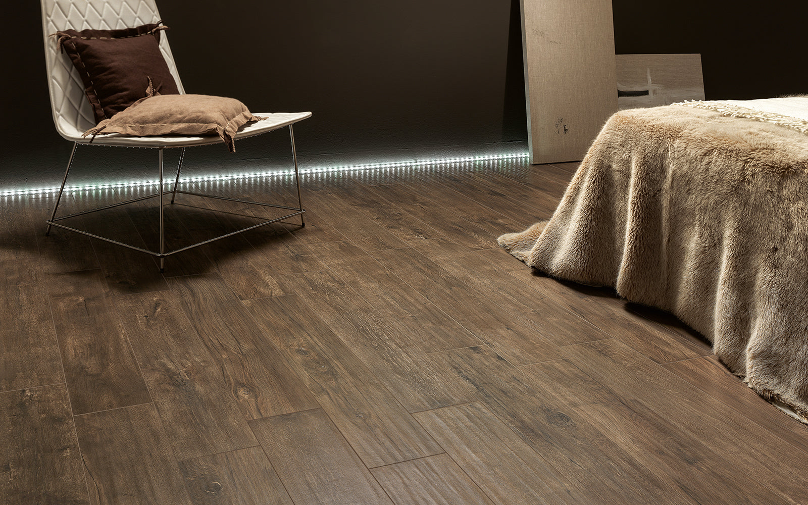 Wooden flooring in a room with a chair and bed.