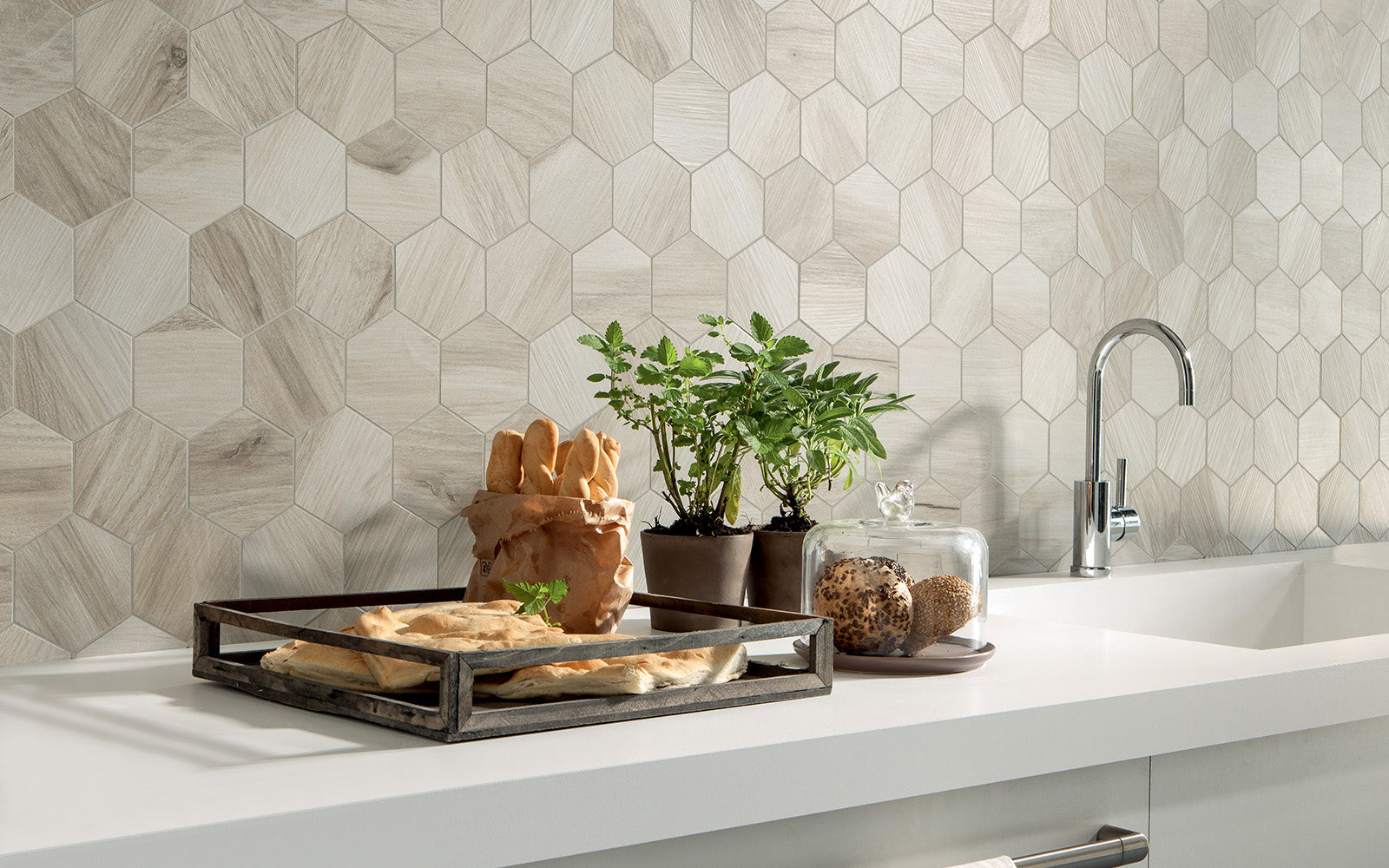 Modern kitchen with hexagonal tile backsplash, white countertops, and various items on the counter.