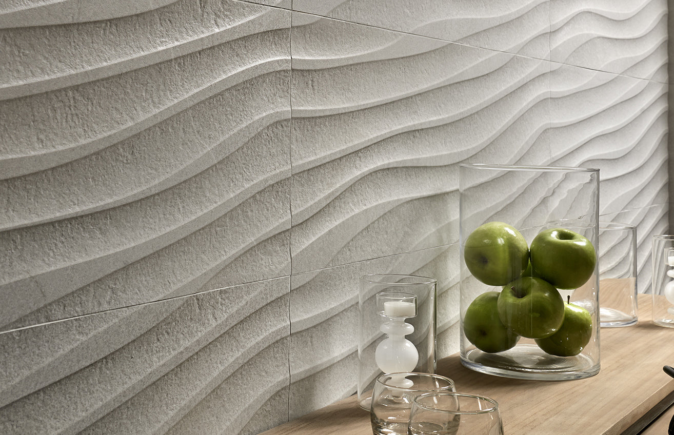Wavy tile pattern on a wall with a glass container holding green apples.