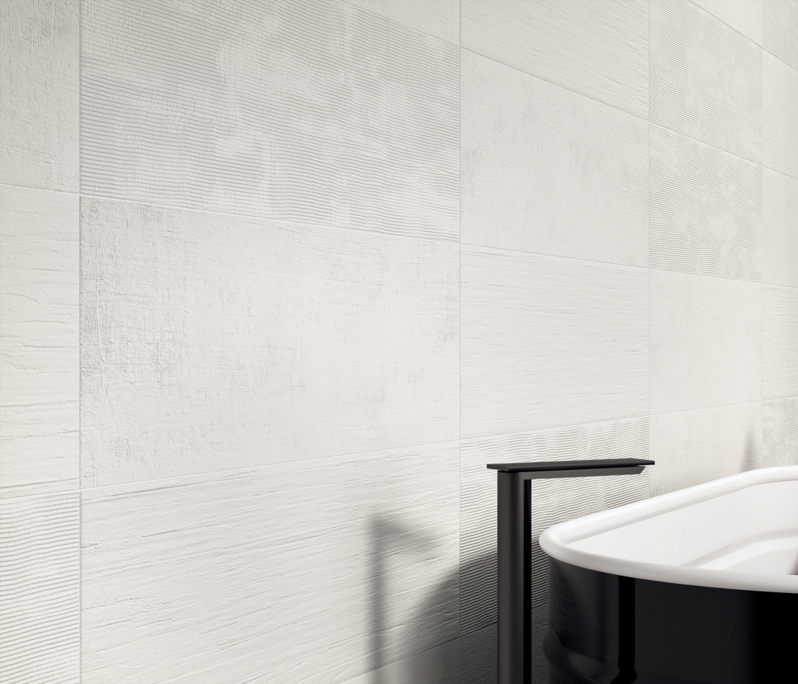 White bathtub against a tiled wall with a black faucet.